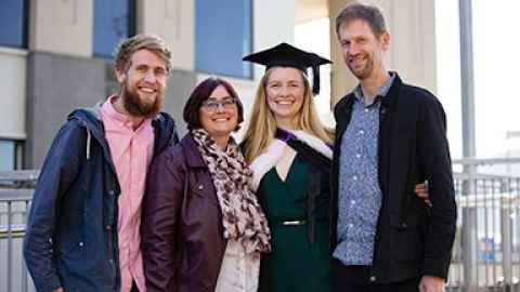 Hanna Davidson in graduation regalia, and three other people.