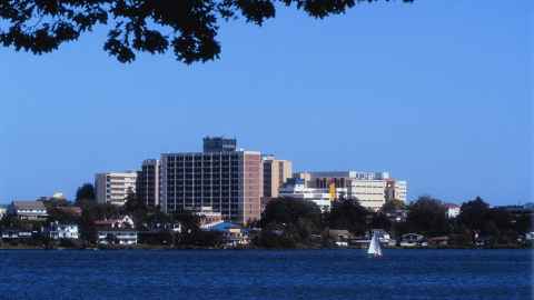 The image show aikato Hospital from across the river, against a clear blue sky. Photo: Hamilton City Council via Wikicommons