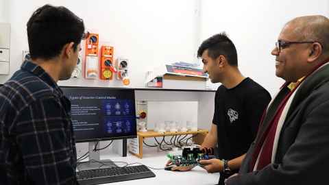 Three men looking at a computer.