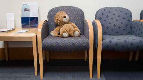 Stuffed animal toy on a chair in a waiting room.