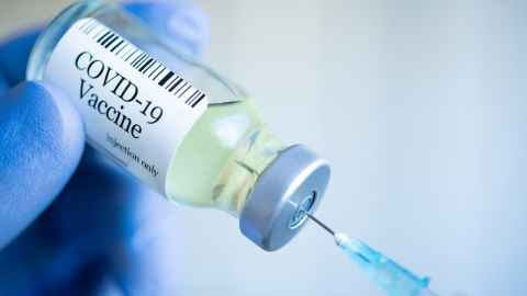 A syringe in a vial labelled 'Covid-19 vaccine'.