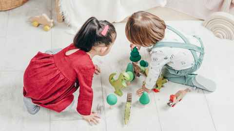 Two children playing with toys on the floor.