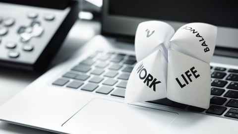 A laptop with a paper fortune teller with 'Work', 'Life', 'Balance' and '?' on it.
