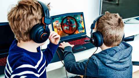 Two children playing a game on a laptop.