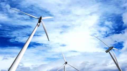 Wind turbines against a blue sky with white clouds.