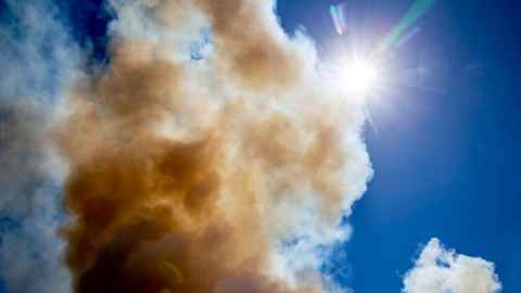 Sun and blue sky behind a cloud of smoke