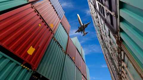Shipping containers, with a plane flying overhead.