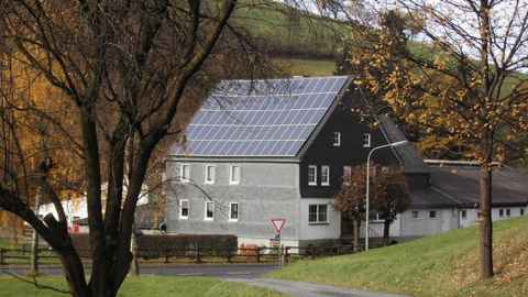 An old house with solar panels on the roof.