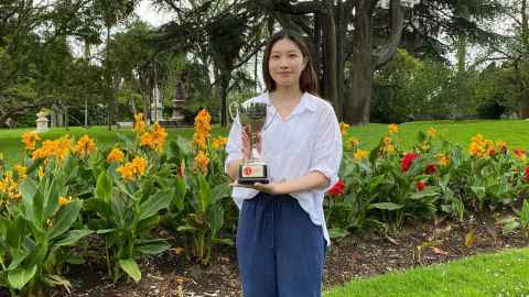A young woman in Albert Park, holding a trophy.