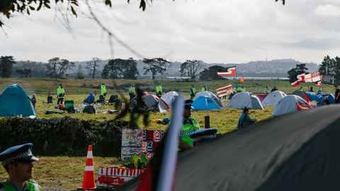 Tents pitched on a field, surrounded by police.