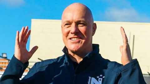 A bald man with his hands in the air.