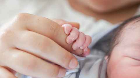 An adult holding a baby's hand.