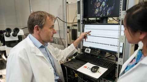 Professor Julian Paton points to a heart rate monitor, with another doctor looking on.