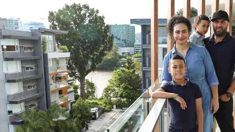 A family on a balcony overlooking other buildings and a river.