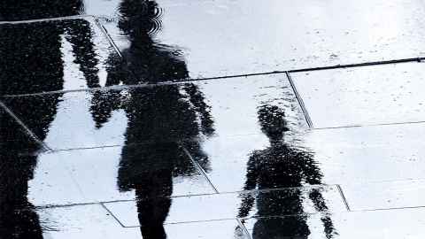 Children's shadows on a rainy pavement.