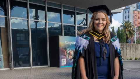A young woman in graduation regalia.