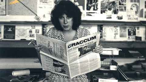 A woman holding a copy of Craccum, smoking a cigarette, photographed in black and white.