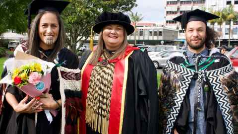 Three people in graduation regalia.