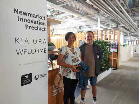 A man and a woman standing beside a sign that reads: Newmarket Innovation Precinct.