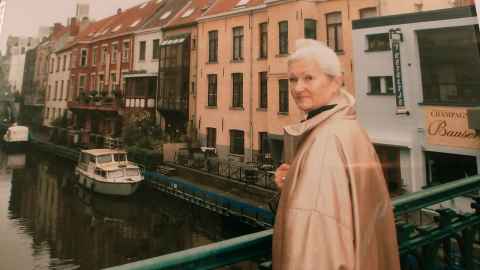 A woman standing on a bridge over a canal.
