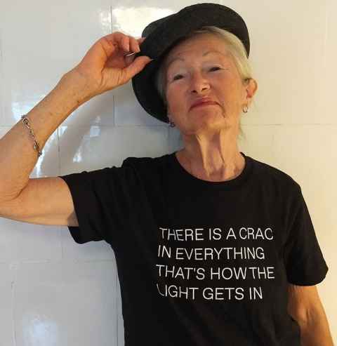A woman in a t-shirt that reads: There is a crack in everything, that's how the light gets in.