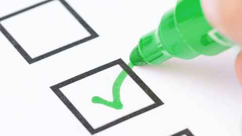A person ticking a box with a green marker pen.