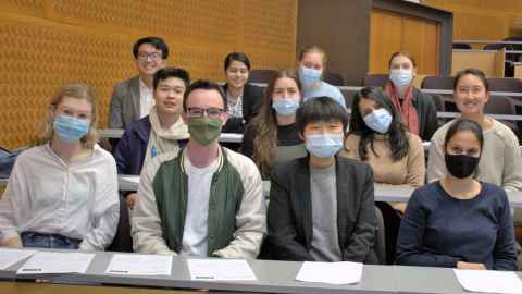 A group of people in a lecture theatre; most are wearing face masks.