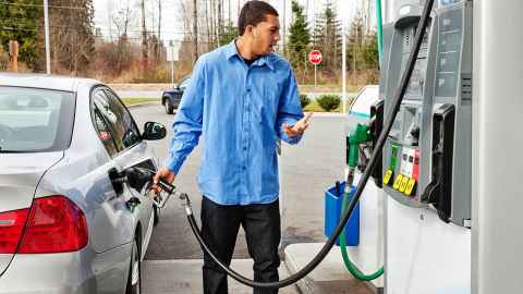 A man pumping petrol, looking shocked at the price.