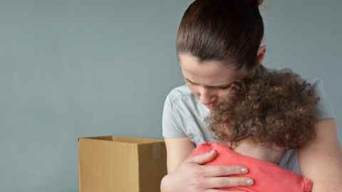A woman hugging a child, with a cardboard box in the background.