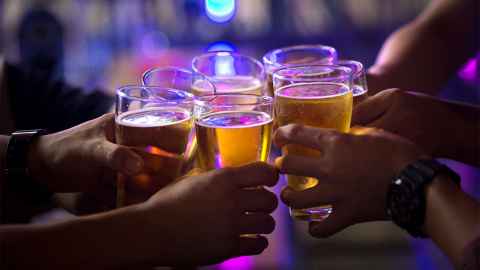 A group of people (only their arms can be seen) holding glasses of beer.