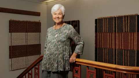 Maureen Lander, with weaving on display behind her.