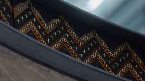 A woven panel with a zigzag design in black, brown, red and yellow.