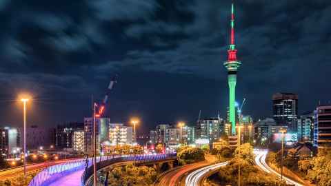 Auckland City at night, with motorways and the Skypath in the foreground.