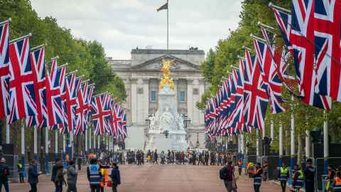 Buckingham Palace, with Union Jacks flying along the road leading to it.