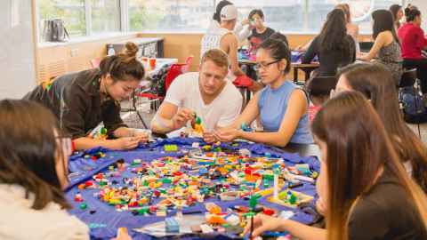 A group of people around a table covered in Lego