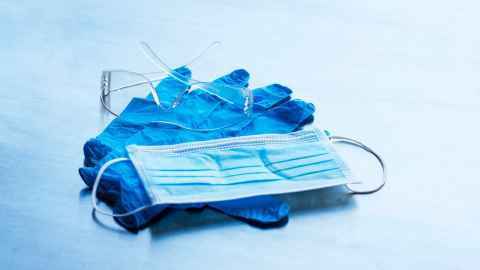 A pair of blue latex gloves, surgical mask and clear plastic protective glasses.