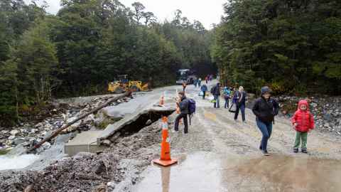 People walking down a flood-damaged road.