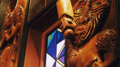 Māori carvings either side of a stained glass window.