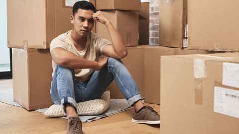 Man sitting among packing boxes as he moves house.