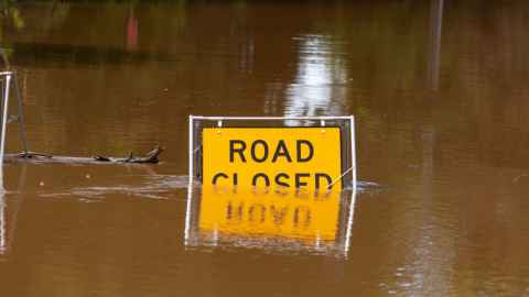 Dirty water up to the middle of a sign that reads: Road closed.
