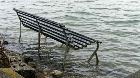 A park bench sitting in floodwater.