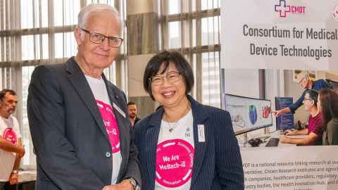 A man and woman smiling, beside a CMDT sign.