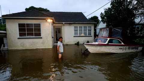 A man in thigh-deep water in front of a house.