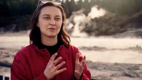 A woman in front of muddy hot springs.
