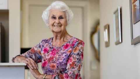 Annette Wilson was a teacher for 70 years.  Pictured at home looking happy, wearing a floral pink top. 