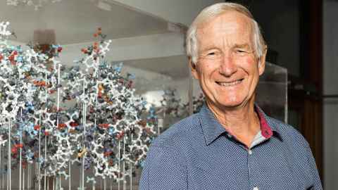  Ted Baker smiling in front of a chemistry molecule representation. 