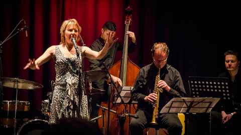 Caro Manins and Roger in performance. She is singing, he's playing sax