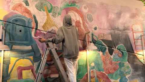 Izzy Hey painting a mural