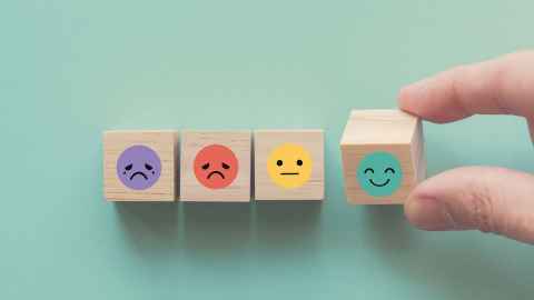 Wooden blocks with happy, sad, crying and neutral faces.