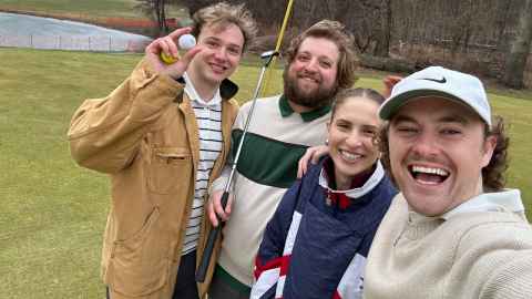 Three young men and a woman on a golf course